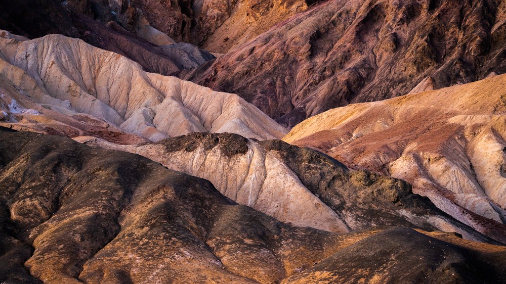 Eroded badland ridges interlock like fingers, warm light on their crests and cool shadow in the folds between.